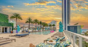 A rooftop pool area with lounge chairs, palm trees, and a view of the city skyline at sunset. - Luxury Hollywood Beach Condo w/Stunning Views (Hollywood)