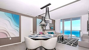 Een moderne woonkamer met een eetgedeelte, grote ramen en uitzicht op de oceaan.