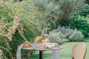 A round table set outdoors with a variety of food items and a chair. - Villa Gatta Bianca - Villa with Pool in Natural Park near Rome (Formello)
