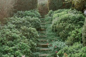 A garden pathway with neatly trimmed hedges and a wooden staircase. - Villa Gatta Bianca - Villa with Pool in Natural Park near Rome (Formello)