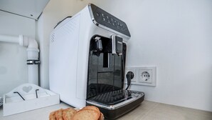 Une machine à café avec un réservoir d’eau, une verseuse et un plateau de biscuits.