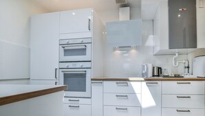 Une cuisine moderne avec des meubles blancs, des appareils en acier inoxydable et un plan de travail en bois.