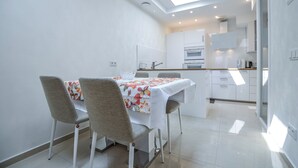 Une cuisine compacte avec des meubles blancs et un coin repas comprenant une table et des chaises.