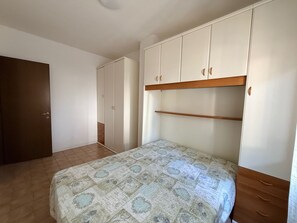 A bedroom with a bed, a wardrobe, and a door. - Nice Familiar Flat in Rosolina Mare (Rosolina)