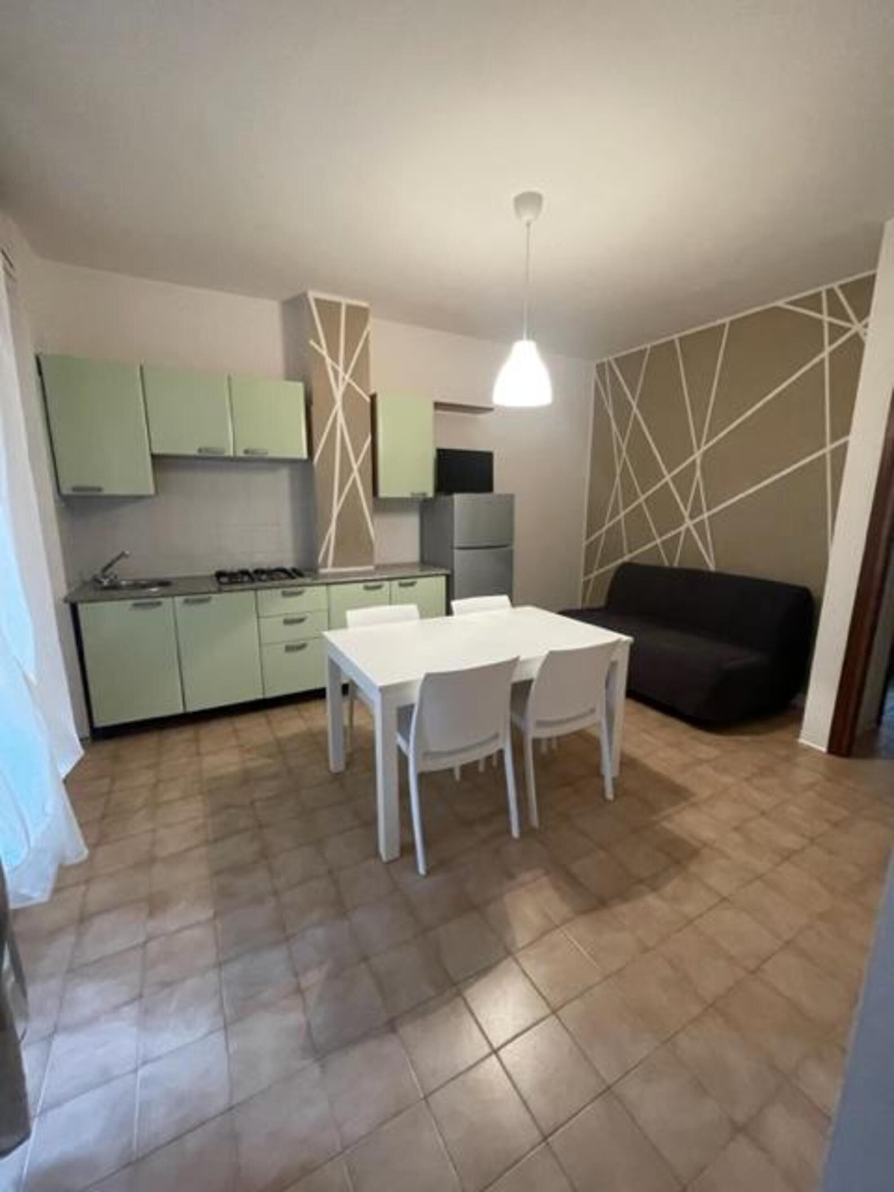 Una cocina compacta con comedor, un sofá e iluminación colgante.