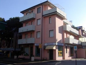 A multi-story building with balconies, a storefront, and a parking sign. - Nice Familiar Flat in Rosolina Mare (Rosolina)