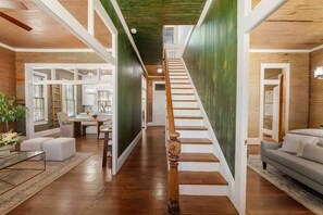 Un interior amplio con una escalera de madera, un comedor y una sala de estar con un sofá.