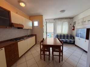 A compact kitchen with a dining area, a sofa, and a view to the outside. - Peaceful Stay Near the Beach in Rosolina Mare (Rosolina)