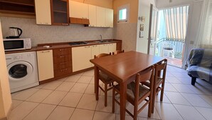 Une cuisine compacte avec un coin repas, un lave-linge et un balcon avec vue.