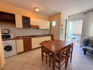 A compact kitchen with a dining area, a washing machine, and a balcony with a view. - Peaceful Stay Near the Beach in Rosolina Mare (Rosolina)