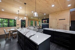 A modern kitchen with a large island, wooden ceiling, and pendant lighting. - 5-Bedroom Cabin with Glow Pool, Arcade Loft & Hot Tub, Sleeps 12 (Sevierville)