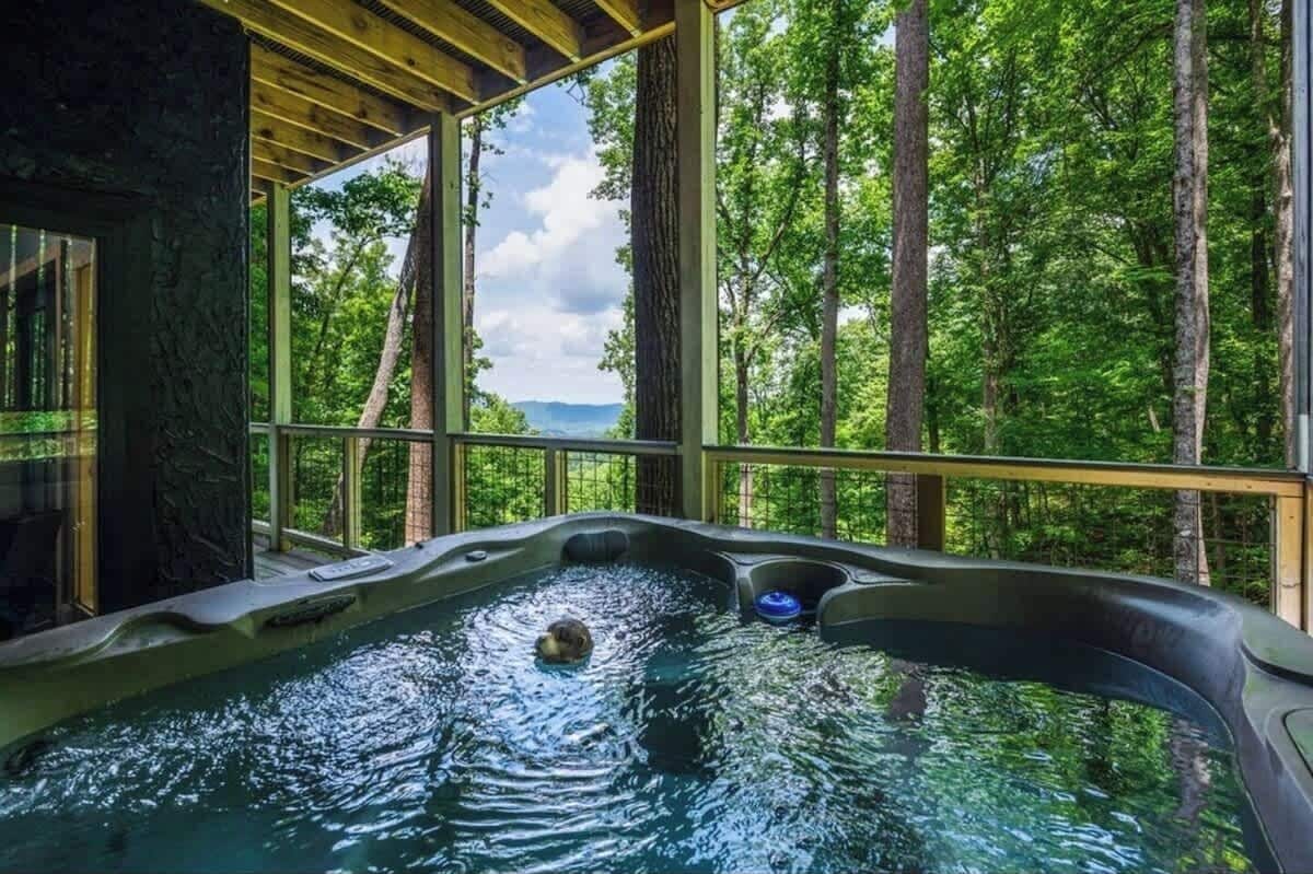 A hot tub with a view of a forest and mountains.