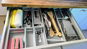 A drawer with kitchen utensils and cleaning supplies.