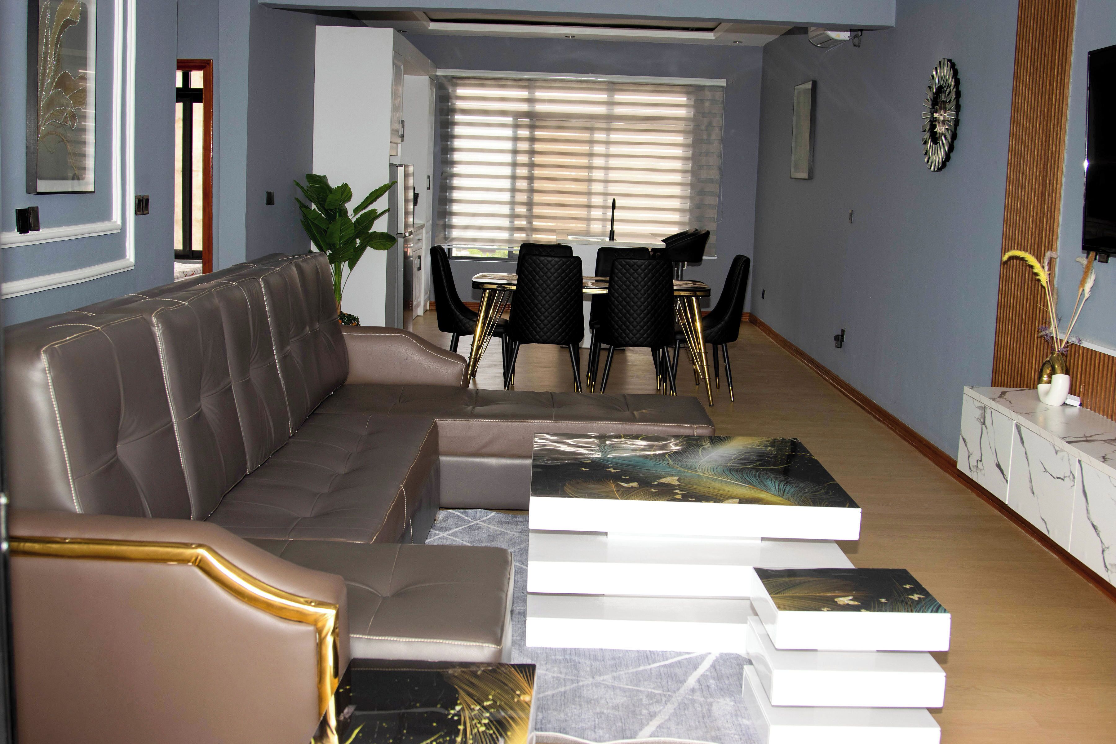 Una sala de estar moderna con un sofá, una mesa de comedor, sillas y un televisor.