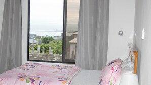 A bedroom with a bed, a window, curtains, and a lamp. - K&K Luxurious Landing (Limbe)