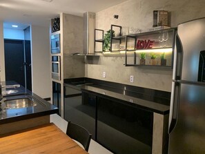 Una cocina moderna con un refrigerador de acero inoxidable, un horno empotrado y una mesa de comedor de madera.