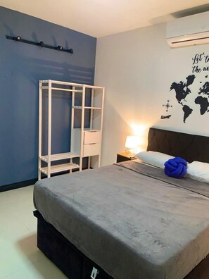 A bedroom with a bed, a white wardrobe, a wall-mounted shelf, a nightstand with a lamp, and a world map decoration. - CASA PREMIUM - ARRAIAL DO CABO - RJ (Arraial do Cabo)