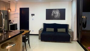 A modern living space with a kitchen area, a dining table, a sofa, and a large framed artwork on the wall. - CASA PREMIUM - ARRAIAL DO CABO - RJ (Arraial do Cabo)