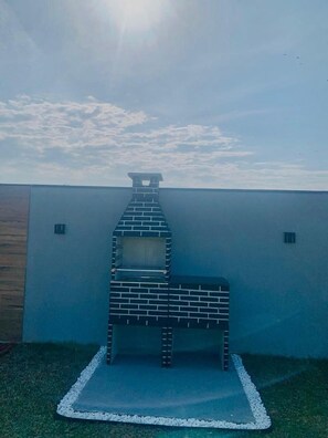 En tegelbyggnad som liknar en skorsten, placerad mot en enkel vägg, med en klar himmel ovanför.