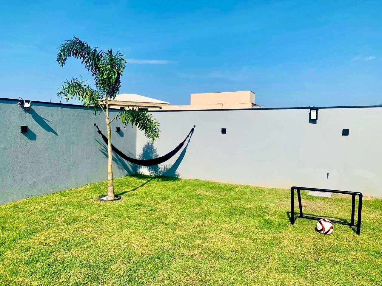 A grassy area with a hammock, a soccer goal, and a wall.