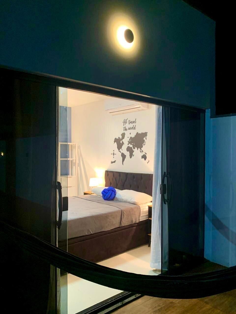 A room with a bed, a map on the wall, and a window.