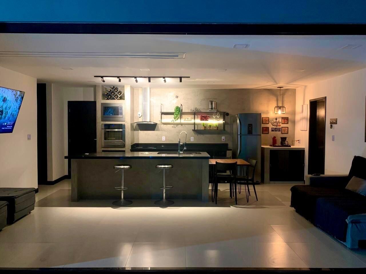 A modern kitchen with a central island, bar stools, and a dining area with a sofa and chairs.