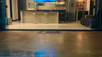 Uma sala de estar moderna com televisão, cozinha e piscina.