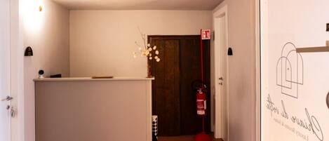 A hallway with a reception desk, a fire extinguisher, and a door with a sign.