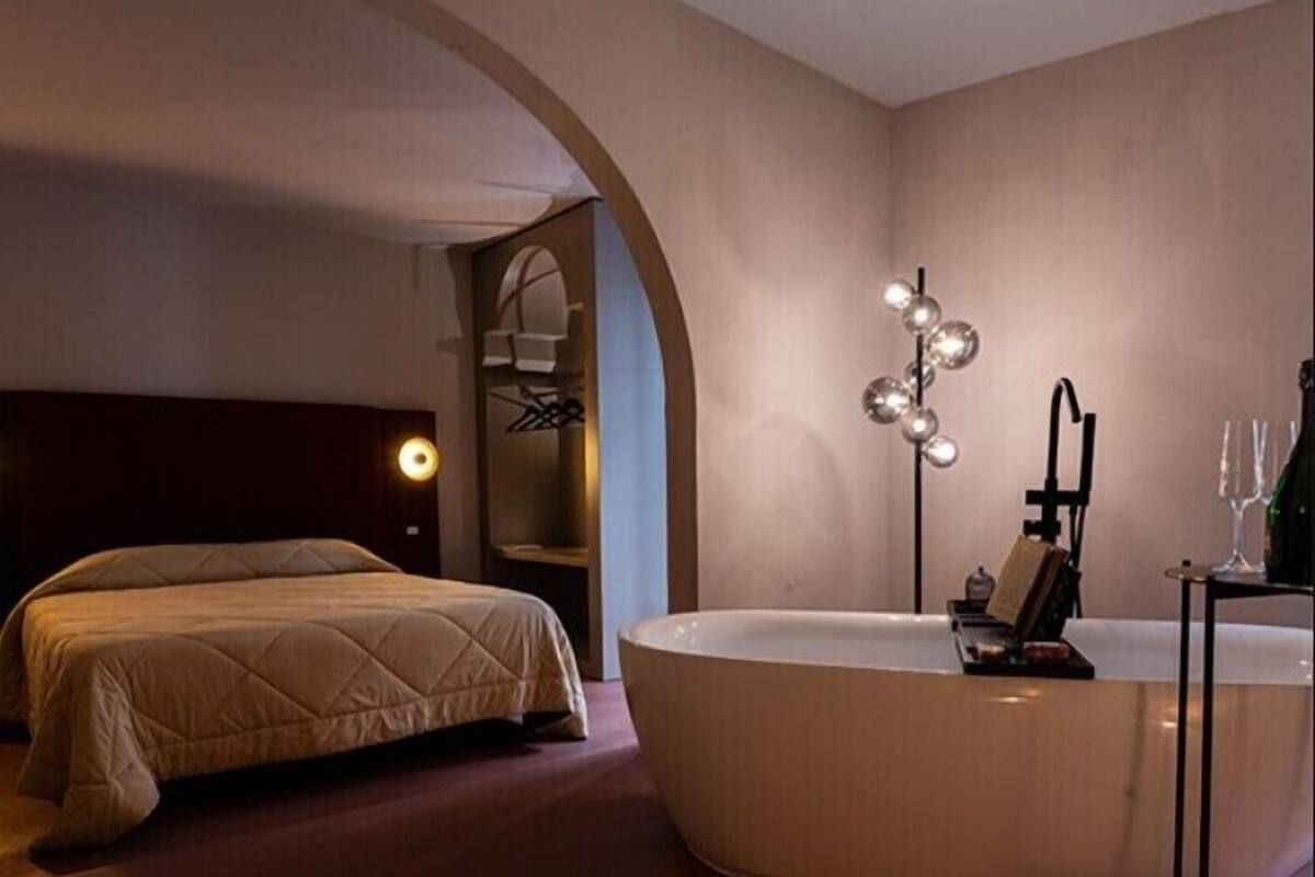 Ein Schlafzimmer mit einem Bett, einer großen Badewanne und einem Spiegel.