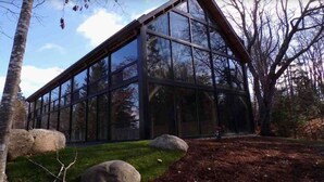 Un bâtiment moderne doté de grandes fenêtres en verre, entouré d’arbres et de rochers.