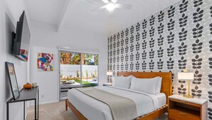 Una camera da letto moderna con un letto, un comodino e una TV montata a parete.