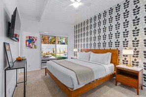 A modern bedroom with a bed, bedside table, and a TV mounted on the wall. - Mid-Century Oasis – Palm Springs Pool Retreat (Palm Springs)