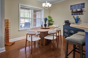 A dining area with a round table, four chairs, a chandelier, a coffee machine, and a bar counter. - Comfortable and Fun 3 BR Home Close to Park, Golf, and Charming Downtown Aiken (Aiken)