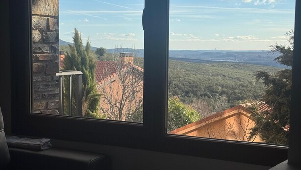 A room with a large window offering a view of a mountainous landscape and a distant city skyline. - Apartment in Berzosa del Lozoya with beautiful views (Berzosa del Lozoya)