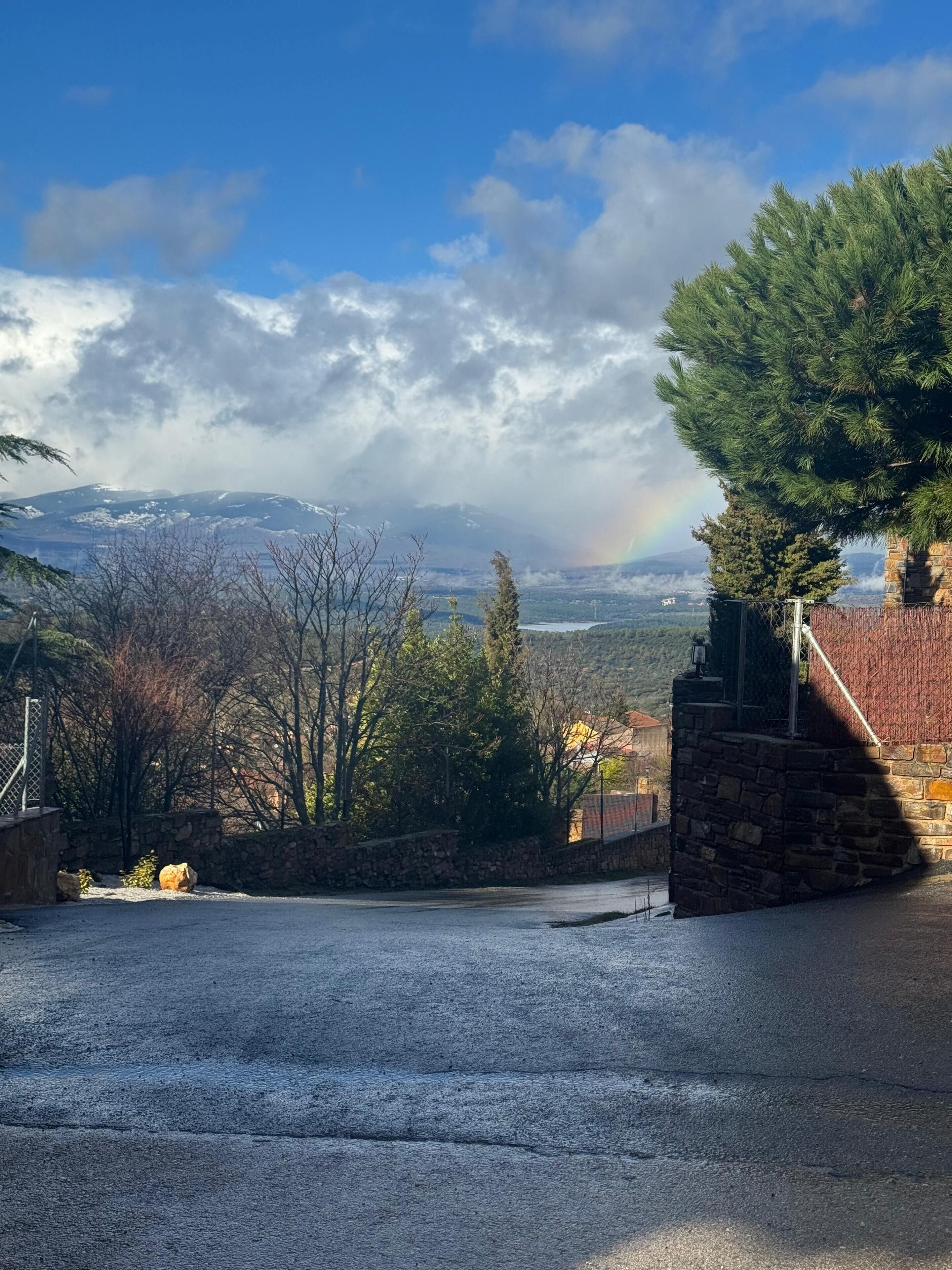 A stone building with a view of mountains and a rainbow.