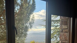 A bedroom with a large window overlooking a mountainous landscape and a tree with yellow leaves. - Apartment in Berzosa del Lozoya with beautiful views (Berzosa del Lozoya)