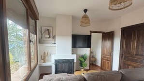 A modern living room with a large sectional sofa, a fireplace, and a kitchen in the background. - Apartment in Berzosa del Lozoya with beautiful views (Berzosa del Lozoya)