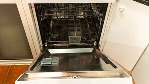 Uma cozinha com forno embutido, torradeira e chaleira vermelha na bancada.