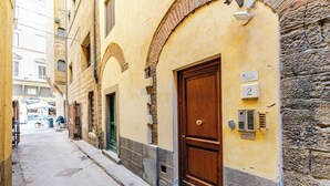 A narrow street with a building featuring a wooden door and a number plaque. - Bright loft with elevator in the historic center of Florence (Firenze)