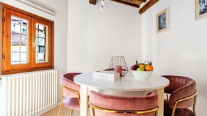 A round dining table with a white tablecloth, pink upholstered chairs, a white bowl with fruits, and a 'TEA' sign. - Bright loft with elevator in the historic center of Florence (Firenze)