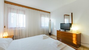 Een hotelkamer met een bed, een televisie, een dressoir, een spiegel en een lamp.