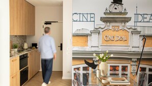 Een moderne keuken met houten kastjes, een koffieapparaat en een eethoek met een glazen tafel en stoelen.