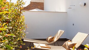 Een terras op het dak met twee loungestoelen, een bijzettafeltje en een bloempot.