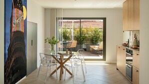 Een moderne keuken met houten kastjes, een glazen eettafel en stoelen.