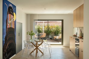 A modern kitchen with wooden cabinets, a glass dining table, and chairs.