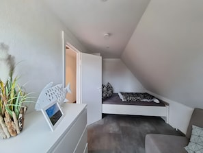 Un dormitorio moderno con una cama elevada, una mesita de noche con un marco de foto y una escultura decorativa de un pez.