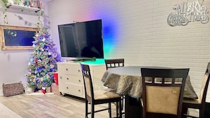 Een eethoek met een houten tafel, stoelen, een televisie en een kerstboom.