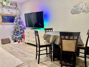 Ein Essbereich mit einem Holztisch, Stühlen, einem Fernseher und einem Weihnachtsbaum.