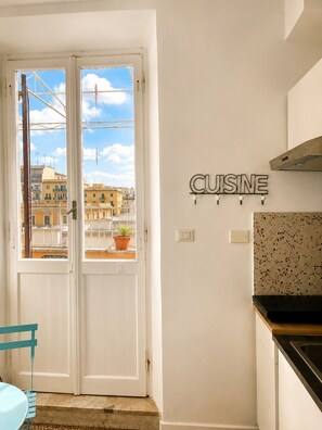 A kitchen with a backsplash, a double door leading to an outdoor balcony, and a wall-mounted sign that reads 'CUISINE'. - CASA FRIDA, cozy bright attic with terrace. (Roma)
