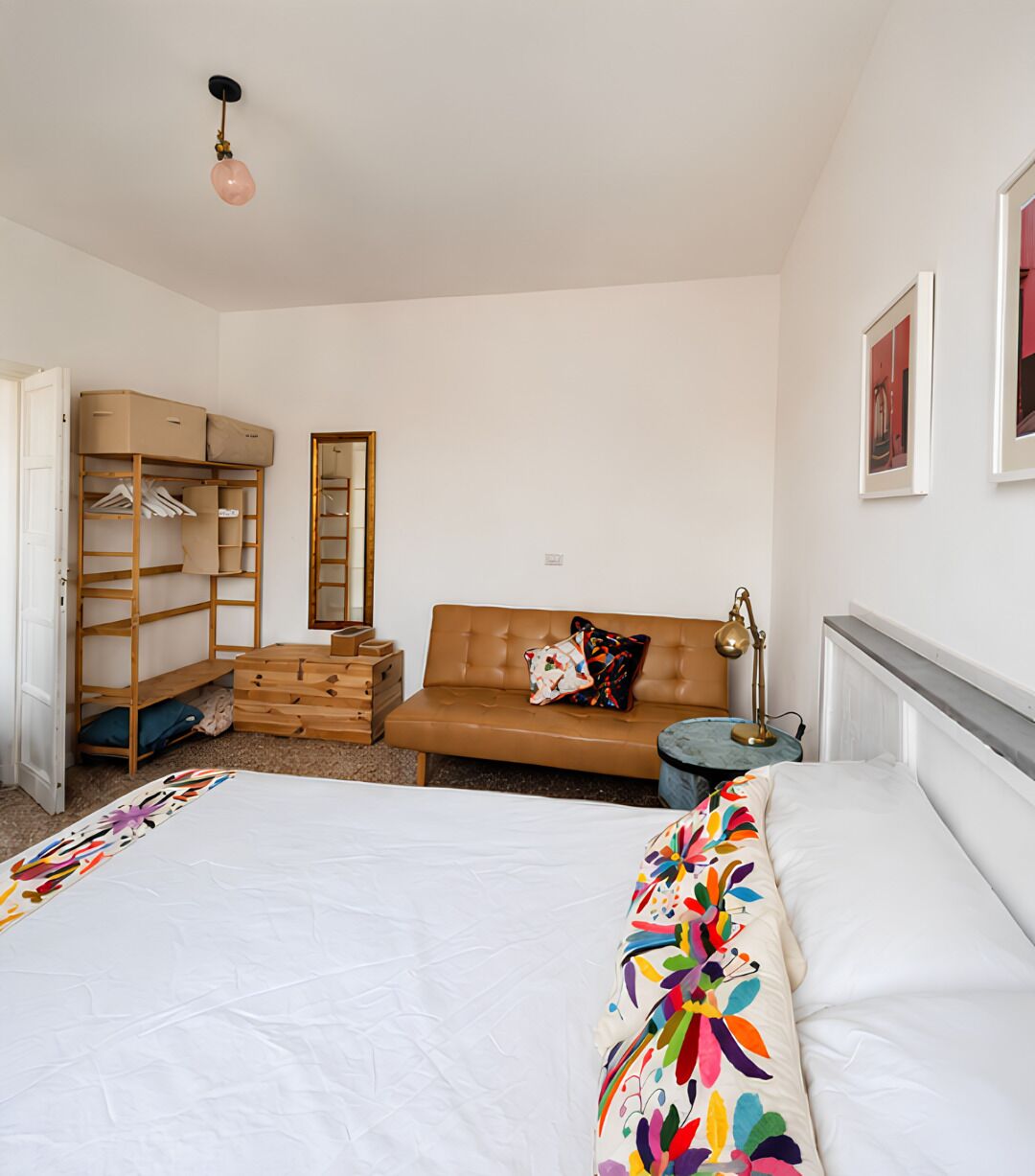 A bedroom with a bed, a sofa, a wardrobe, a mirror, and a lamp.